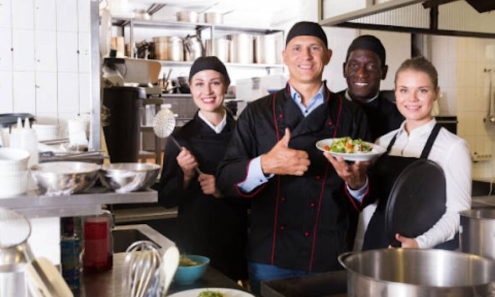 Chef inspects gleaming chrome steel eating place equipment line interior a modern business kitchen