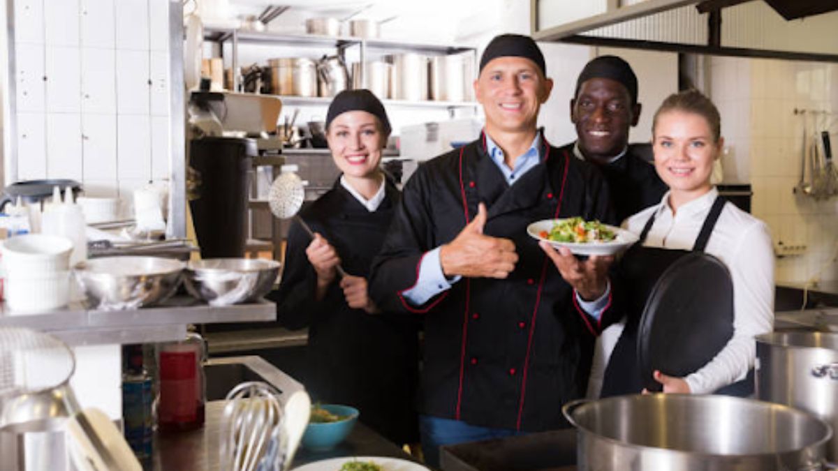 Chef inspects gleaming chrome steel eating place equipment line interior a modern business kitchen